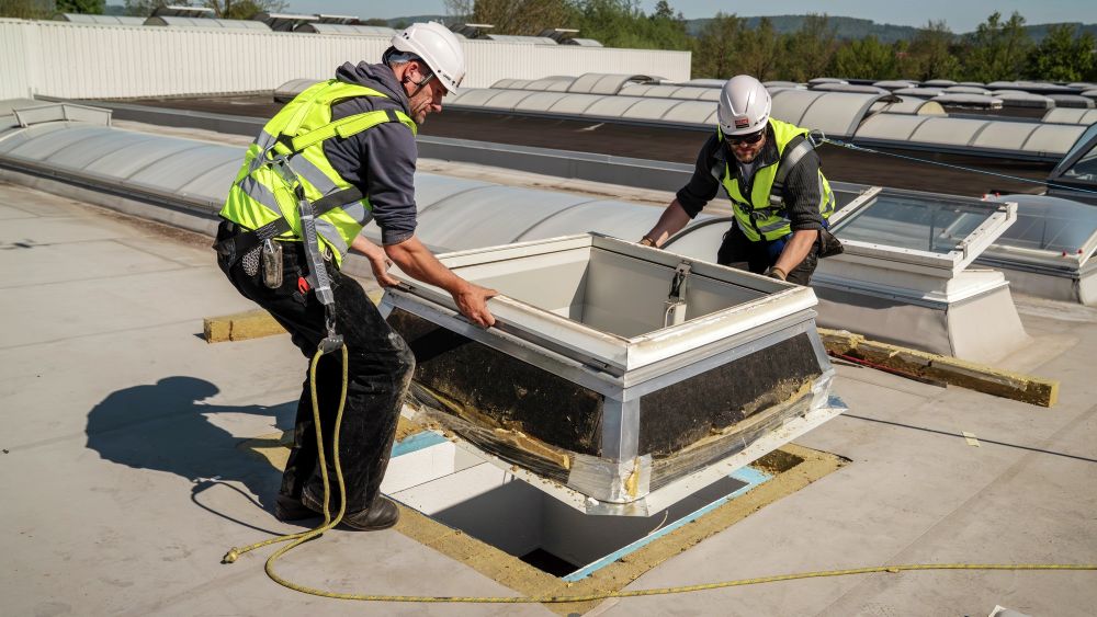 Arbejdere, der monterer et VELUX-dagslys på et fladt tag.